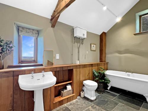 a bathroom with a sink and a tub and a toilet at Widehay Barn Mariansleigh in Mariansleigh