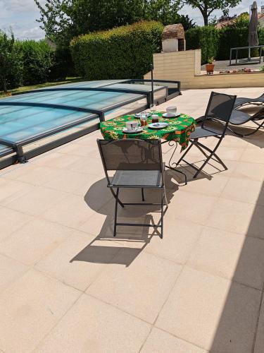 a table and two chairs next to a swimming pool at La revetizon in Saint-Pierre-dʼAmilly