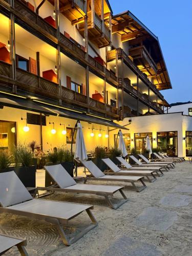 a row of lounge chairs and umbrellas in front of a building at Upside Down Town Hotel Neue Post in Zell am See