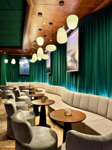 a waiting room with couches and tables and green curtains at Upside Down Town Hotel Neue Post in Zell am See
