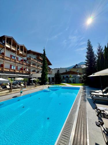 a large swimming pool with chairs and a building at Upside Down Town Hotel Neue Post in Zell am See