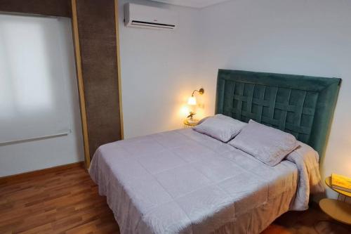 a bedroom with a large bed with a green headboard at El Refugio de la Catedral in Jaén