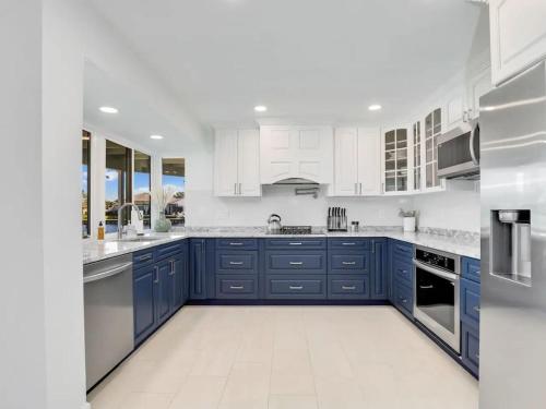 フォートマイヤーズにあるRelax at Lake Breeze 4BR Fort Myers Getawayのキッチン(青いキャビネット、白い電化製品付)