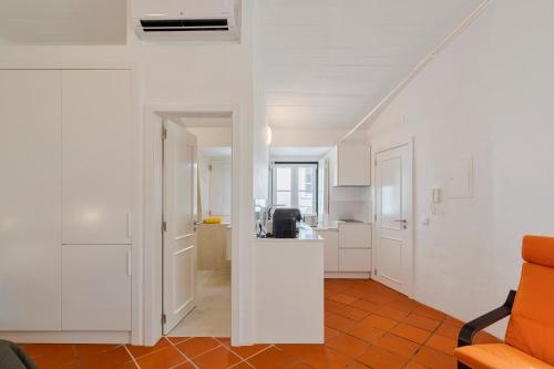 a white kitchen with an orange chair in a room at Sapalinho Retreat - By Y Concept in Setúbal