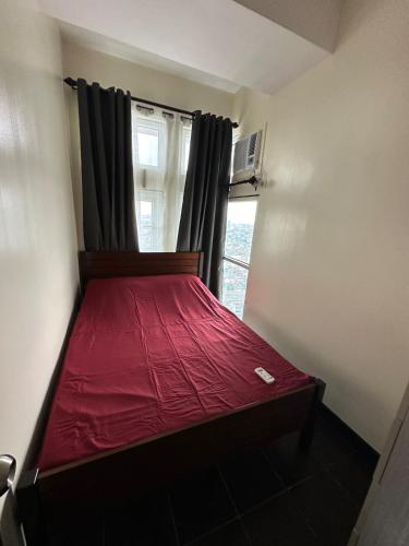 a red bed in a room with a window at 2BR Condo in Makati- Good for 6! in Manila