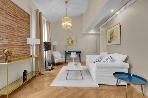 a living room with a white couch and a brick wall at Les Relais du Capitole - Appartements d'hôtes in Toulouse