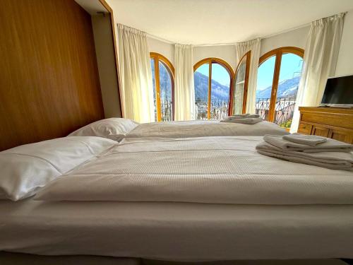 1 cama blanca grande en una habitación con ventanas en Château 15, en Leukerbad