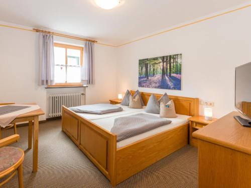 1 dormitorio con cama, mesa y TV en Pension Landhaus Koller - Adults only, en Bodenmais