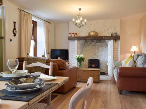 a living room with a table and a fireplace at Moss Cottage in Burry Port