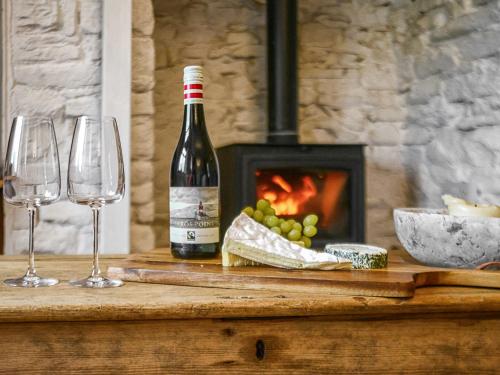 una bottiglia di vino appoggiata su un tavolo con bicchieri da vino di Moss Cottage a Burry Port