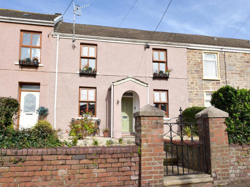 una casa in mattoni rosa con recinzione di mattoni di Moss Cottage a Burry Port