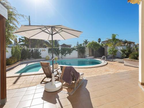 a patio with an umbrella and chairs and a pool at Costa de la Luz Poolside Villa in Sanlúcar de Barrameda