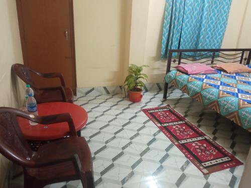 a room with a bed and a chair and a table at Ghosh homestay 8 in kolkata