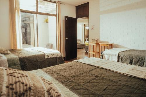 a hotel room with three beds and a window at Central Hostel Metro10 in Guatemala