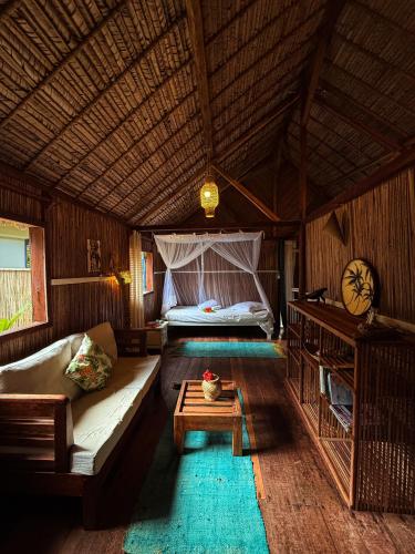 a living room with a couch and a bed at Ravenala Lodge, Bungalow et Maison Ile aux Nattes in Ile aux Nattes