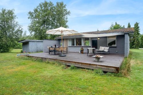a house with a wooden deck with an umbrella at Cozy Holiday Home 350 Meters From The Water In Amtoft in Vesløs