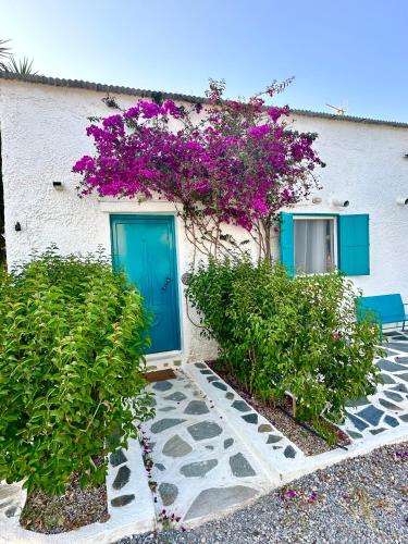 a building with a blue door and purple flowers at Peaceful Cottage House By The Sea - Private Garden in Análipsis