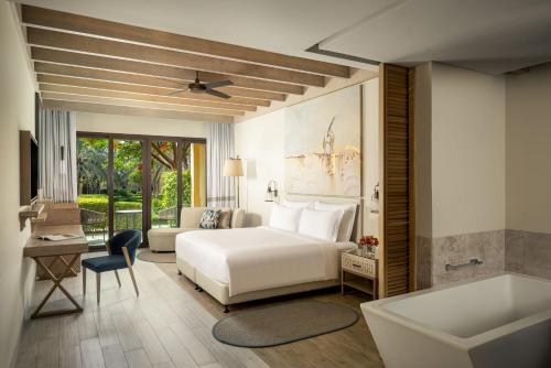 a bedroom with a white bed and a tub at Saadiyat Rotana Resort and Villas in Abu Dhabi