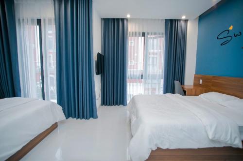 a bedroom with two beds and blue curtains at Cobalt House in Ðông Thôn
