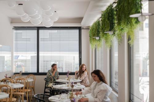 three women sitting at a table in a restaurant at IRA - ΗΡΑ Hotel in Kalamata