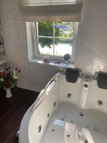 a white bath tub in a bathroom with a window at Gulbės Apartamentai in Anykščiai