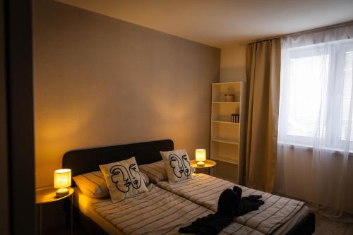 a bedroom with a bed with two lamps and a window at Holiday House Valaliky in Valaliky