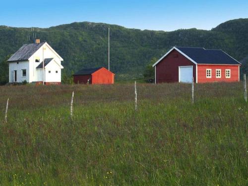 three buildings in a field next to a fence at 7 person holiday home in Bøstad-By Traum in Alstad