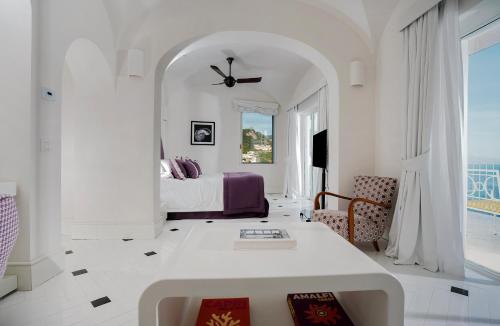 a white room with a bed and a table at Hotel Miramalfi in Amalfi