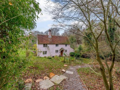 an old white house in the middle of a field at Highlands Farmhouse in Dallington