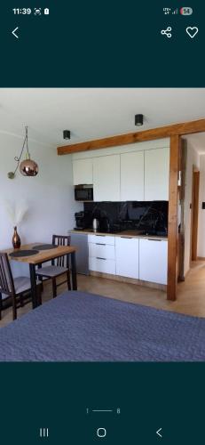 a room with a table and a kitchen with white cabinets at Apartament Laura in Mechelinki