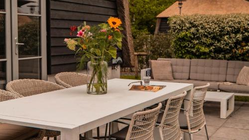 a vase of flowers on a white table with chairs at Dutchen Park Weideduyn in Schoorl