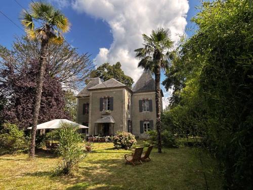 an old house with two palm trees in front of it at Château Lestéous 