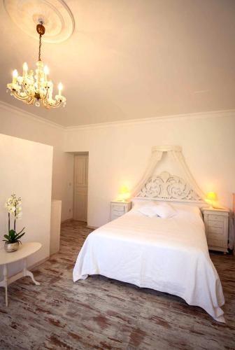 a bedroom with a white bed and a chandelier at Château Lestéous 