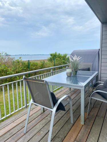 a table and two chairs on a deck with the ocean at Heimathafen in Olpenitz