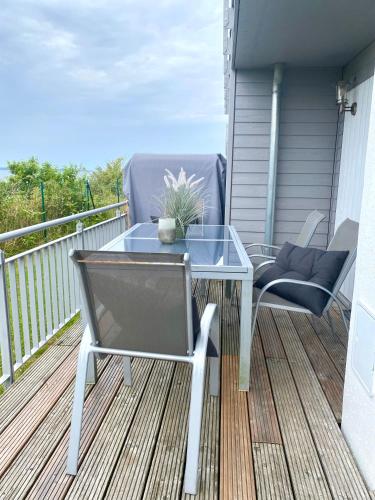 a glass table and chairs on a balcony at Heimathafen in Olpenitz