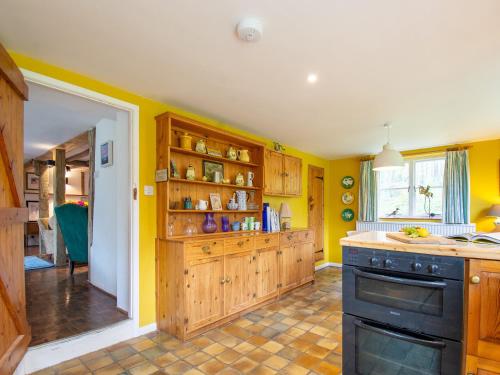 a kitchen with yellow walls and wooden cabinets at Highlands Farmhouse in Dallington