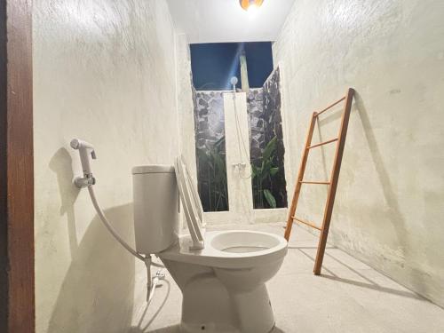 a bathroom with a toilet and a ladder at Mengalung Bungalow in Kuta Lombok