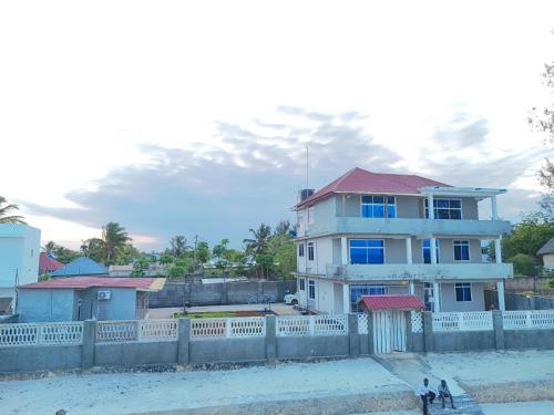 a white house with a fence in front of it at 2BR Beachfront Apartment with Balcony & Sea Views - Uroa, Zanzibar in Uroa