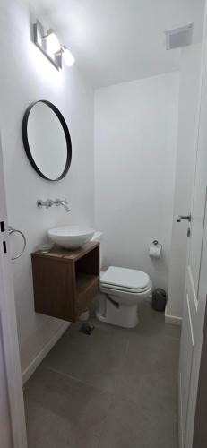 Un baño con lavabo, inodoro y espejo. en Departamento céntrico Pioneros y Campichuelo, en San Carlos de Bariloche