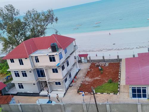 a white house with a red roof next to a beach at 2BR Beachfront Apartment with Balcony & Sea Views - Uroa, Zanzibar in Uroa