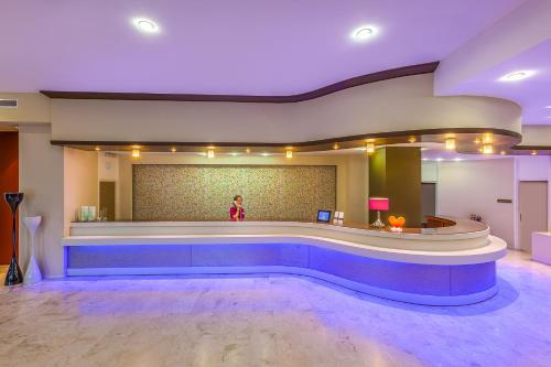 a woman standing in a waiting room with a pool at Kipriotis Hippocrates Hotel in Kos Town