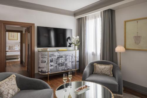 a living room with two chairs and a tv at Hotel Gabrielli Venezia - Starhotels Collezione in Venice