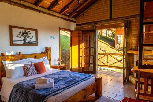 a bedroom with a bed and a door to a patio at Pousada Chales Rancho Caipira in Santo Antônio do Pinhal