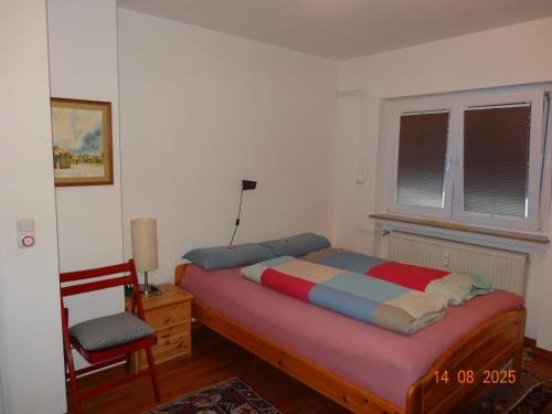 Un dormitorio con una cama y una silla y una ventana. en Kleine Einliegerwohnung- komfort Home!, en Lahnau