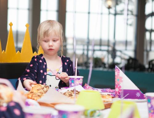 a little girl sitting at a table eating pizza at Quality Hotel Skjærgården in Langesund