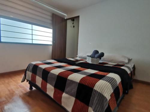 a bedroom with a bed with a checkered blanket at Aparta-estudio cerca UPTC, clínica de los andes in Tunja