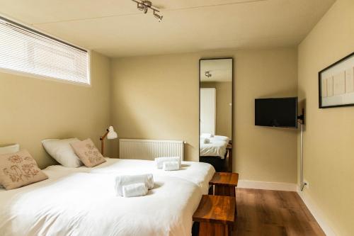a bedroom with two white beds and a television at Dutchen Park Weideduyn in Schoorl