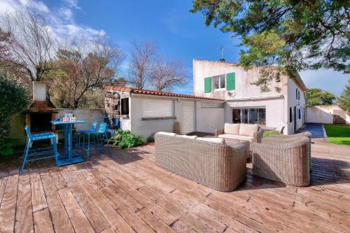 a patio with wicker furniture and a table in a yard at Maison pour 10, accès direct à la plage in Ars-en-Ré