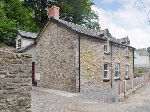 an old stone house with a brick building at Woodlands in Laugharne