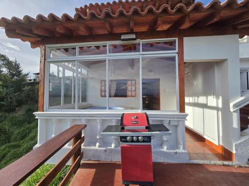 a small house with a red grill on a porch at Luxurious country cabin, BBQ, Jacuzzi, TV, WiFi in Marinilla